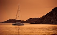 white catamaran sailing during sunset
