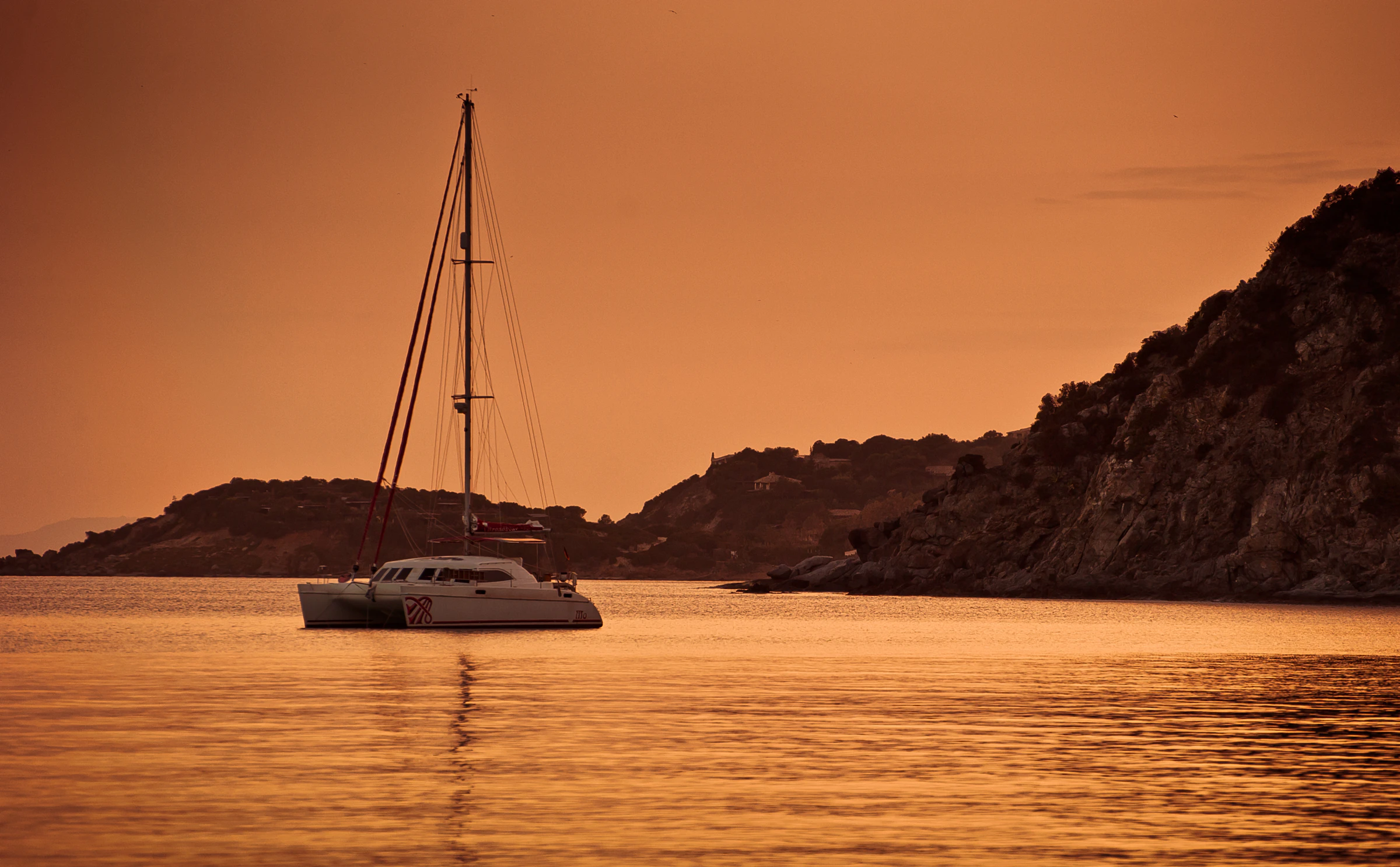 Sailing catamaran at anchor at sunset