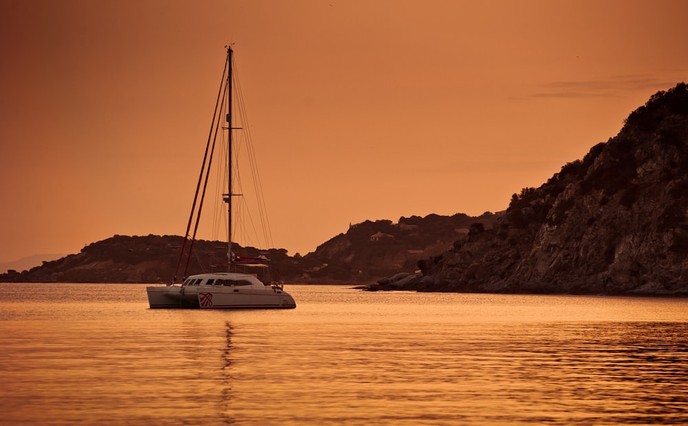 Catamarã branco navegando durante o pôr do sol