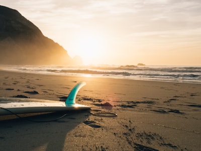 surfboard on brown sand beside ocean during sunset surf google meet background