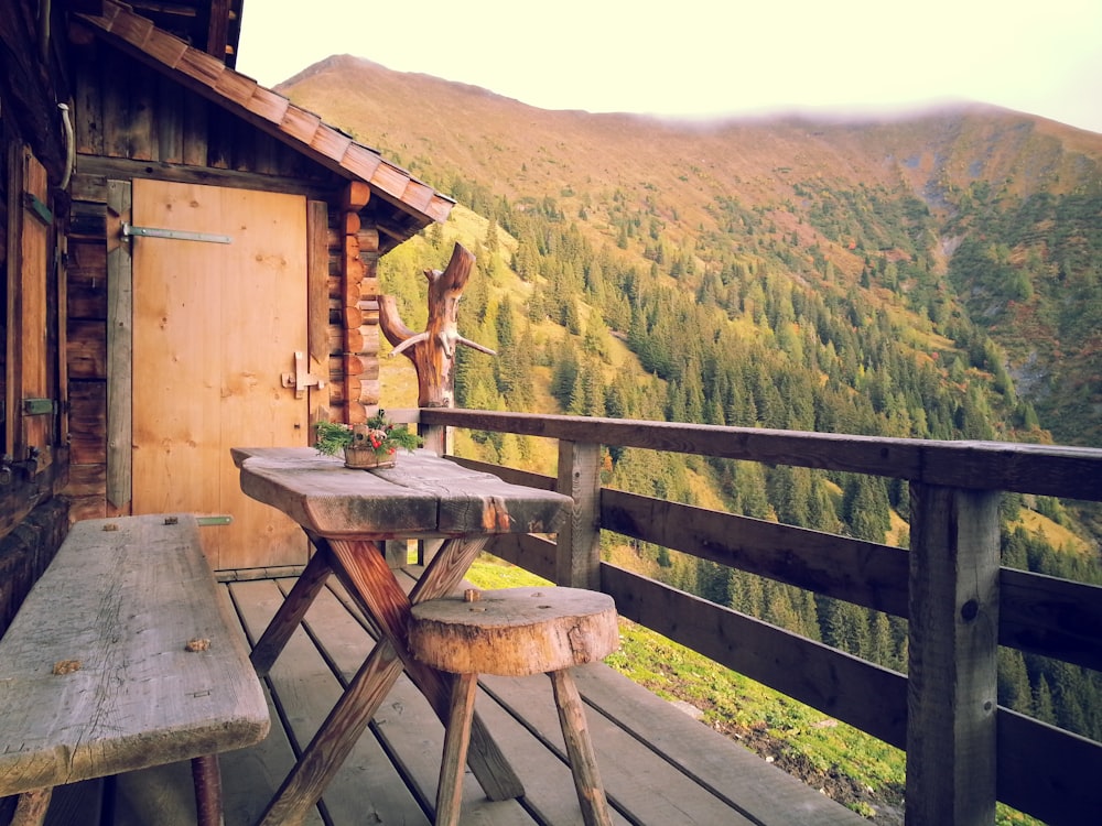 brown wooden table and bench near wooden balcony overlooking mountain at daytime