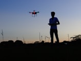 An engineer working on drone technology outdoors at sunset.