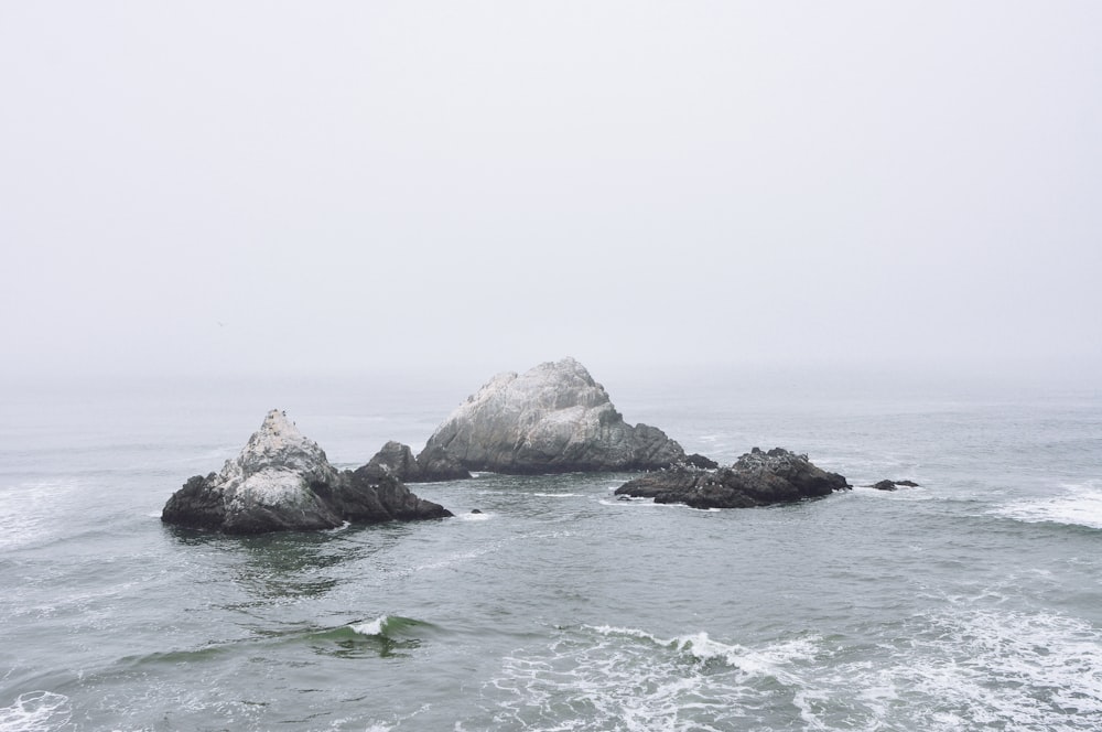 gray and black rock formation in between of body water photo