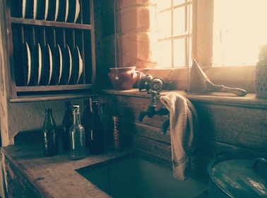 A rustic kitchen countertop with pastel ceramic jars and a vintage wooden cutting board.