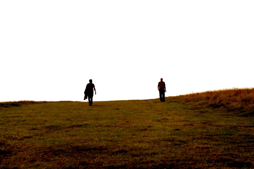 silhouette of two person on hill
