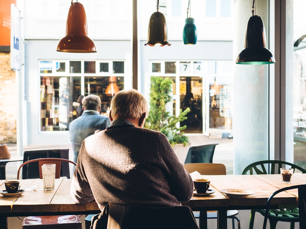 Mann auf Stuhl mit Tisch neben Kaffee