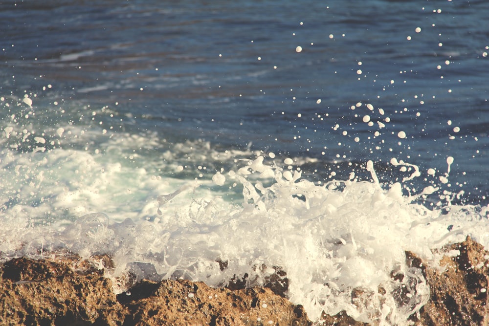 Foto de la ola del mar chocando contra la roca