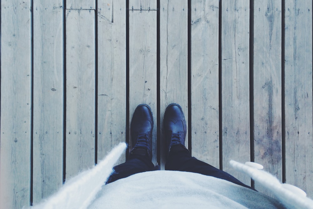 person standing on gray wooden floor