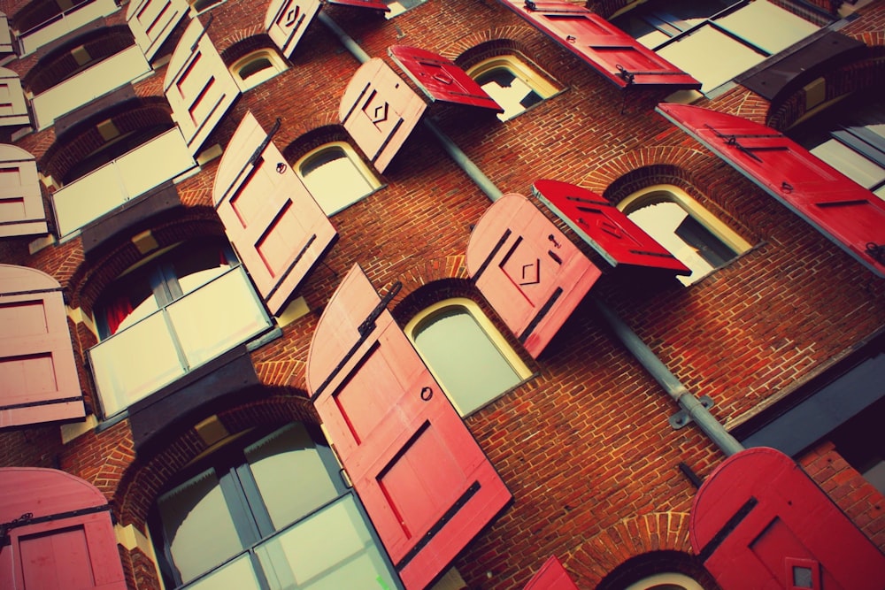 brown brick building with opened red wooden windows during daytime