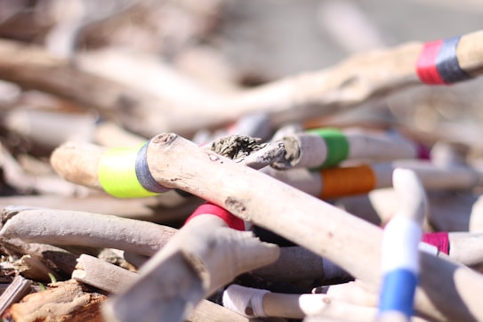 A collection of wooden sticks with various colored bands wrapped around them. The colors include neon green, blue, red, and orange. The sticks appear to be arranged randomly.