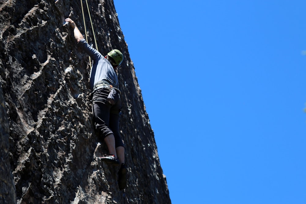 hombre que realiza escalada en la pared bajo el cielo despejado