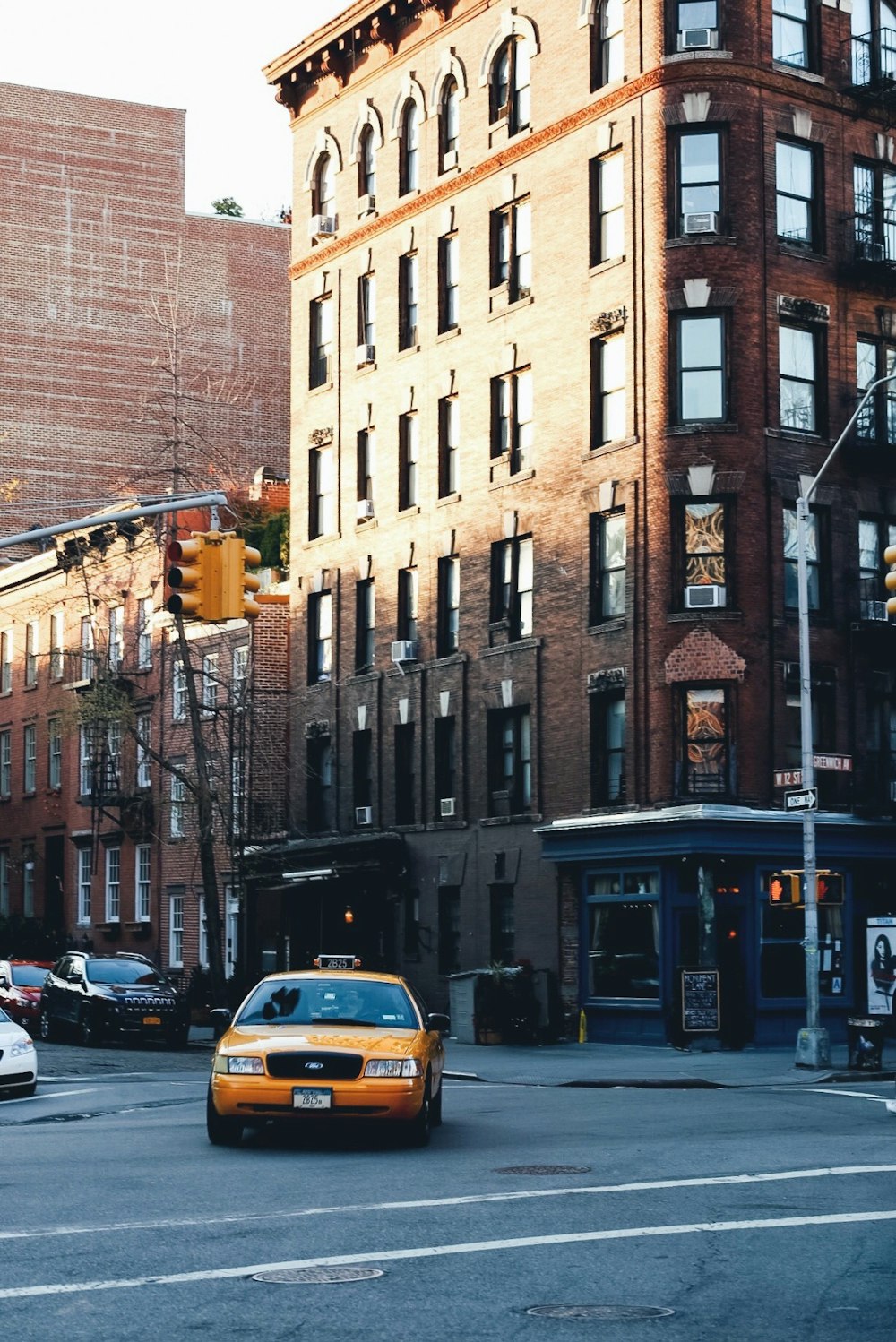 yellow taxi in front of brown brick building during daytime