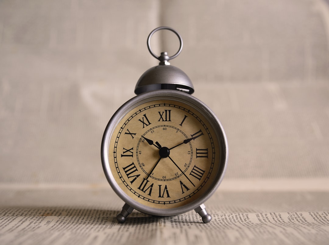 A silver alarm clock with Roman numerals on its face