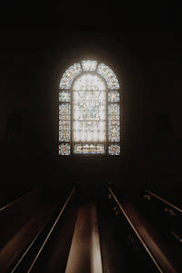 A serene background featuring soft light filtering through stained glass with subtle biblical motifs.