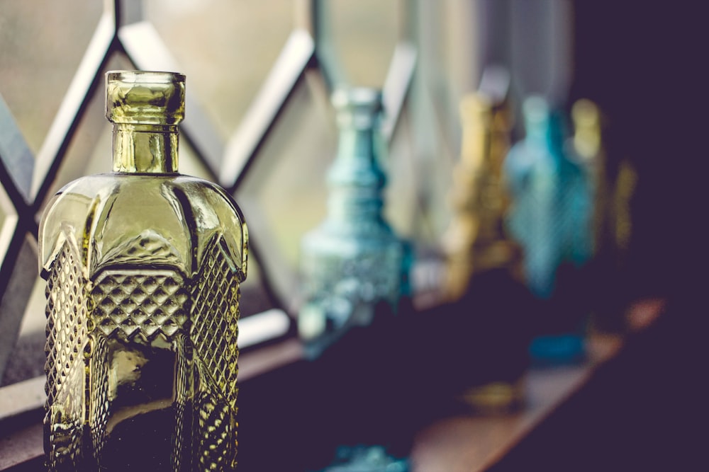 shallow focus photography of yellow glass bottle beside window
