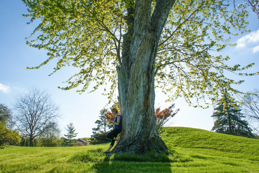 woman leaning on brown wooden tree during daytime