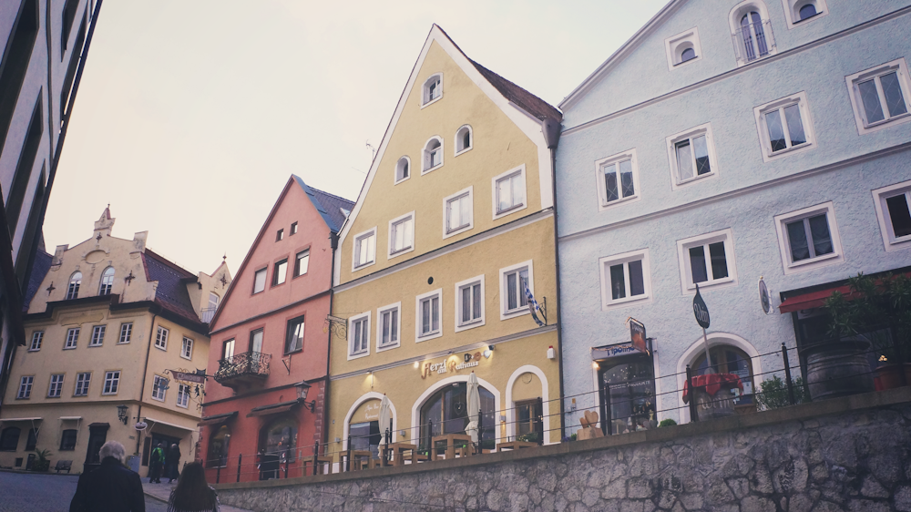 three assorted-color triangular roof houses beside road