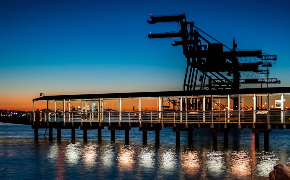 Muelle de madera negra en el cuerpo de agua durante la puesta del sol