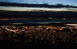 Wide-angle photo of a city skyline at dusk with glowing lights.