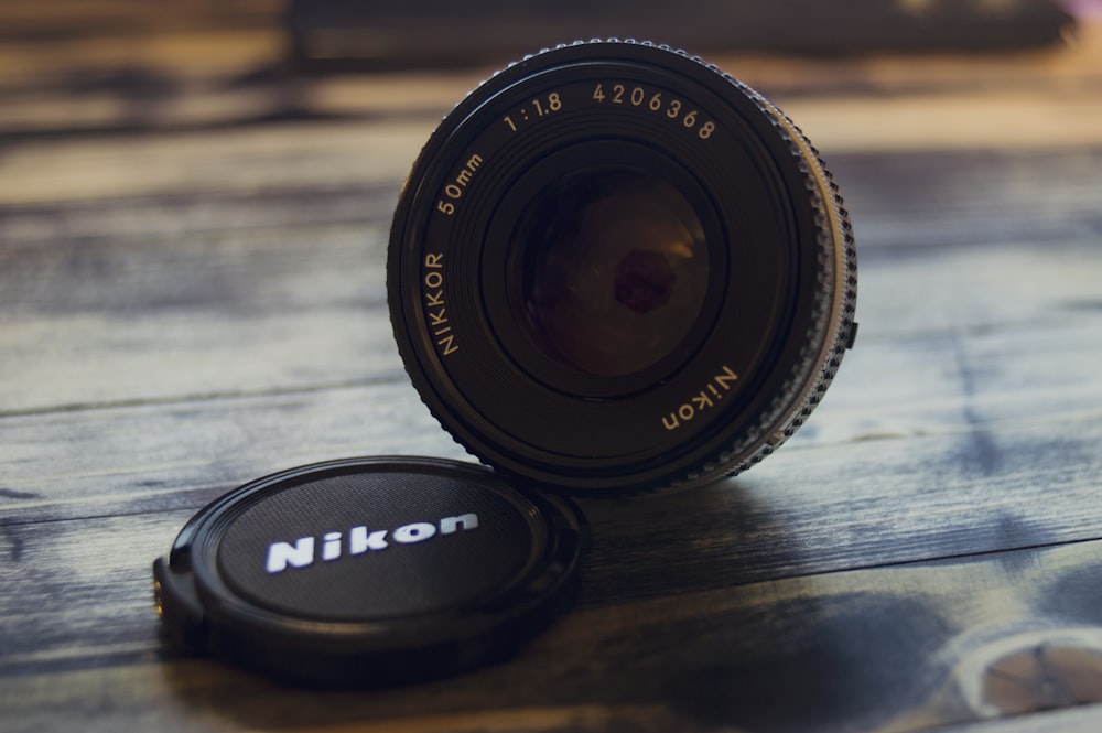 갈색 나무 표면에 검은 색 Nikon 줌 렌즈