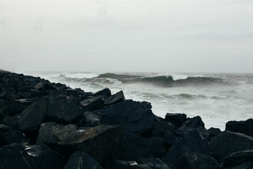 black rock formation near body of water during daytime