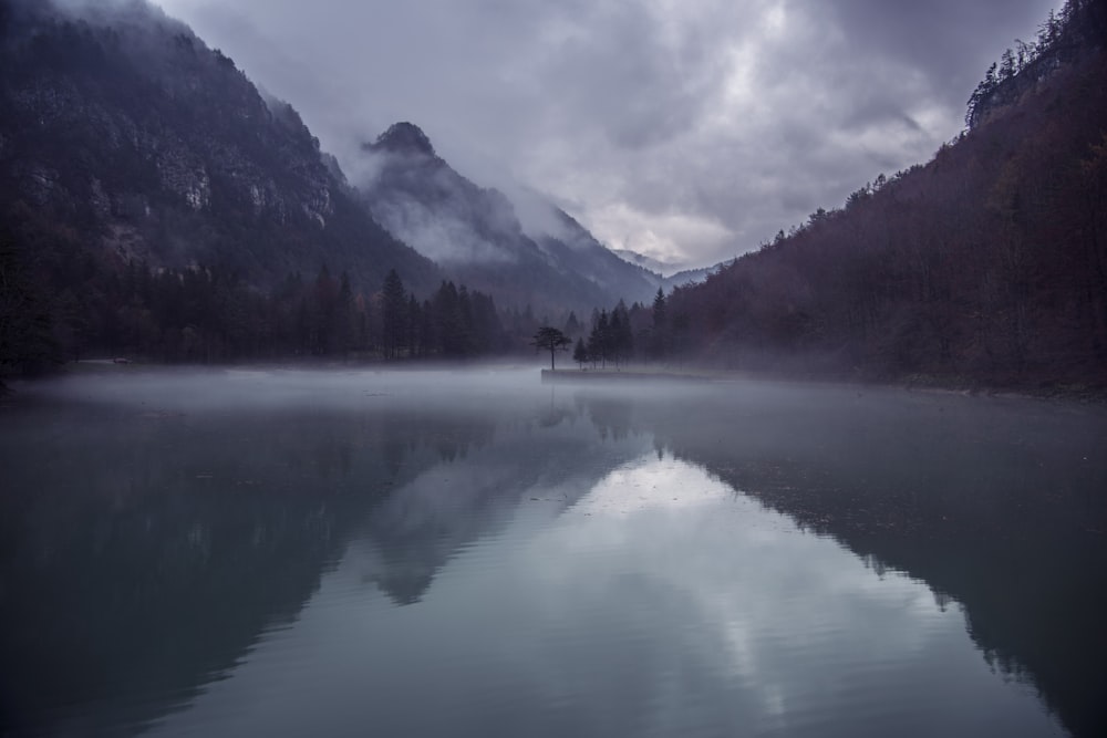 body of water surrounded by mountain during daytime