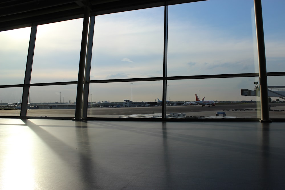 glass panel window showing airplanes and runway under blue sky during daytime