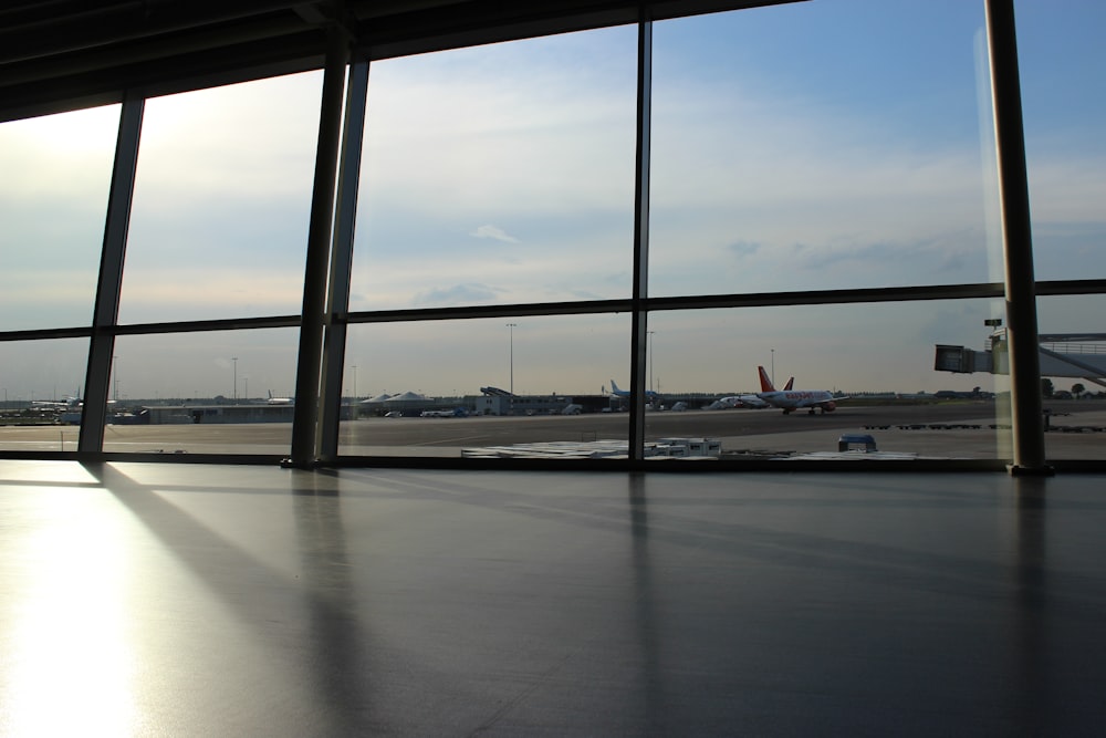 낮에는 푸른 하늘 아래 비행기와 활주로를 보여주는 유리 패널 창