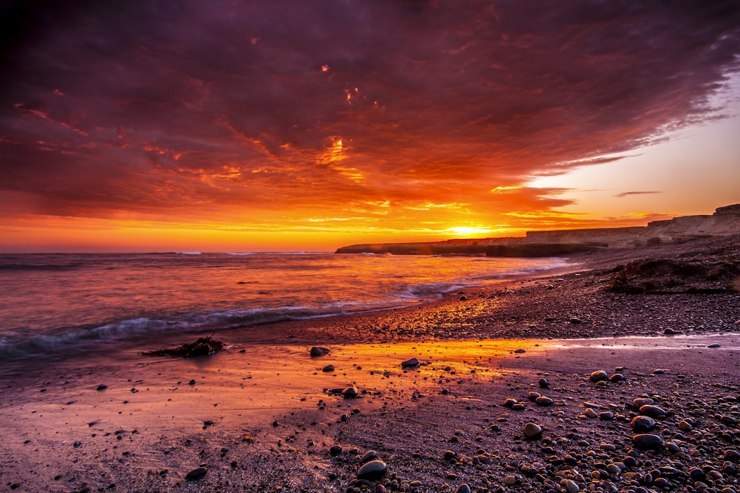 body of water under red sky photo, Fiery sunset over the beach