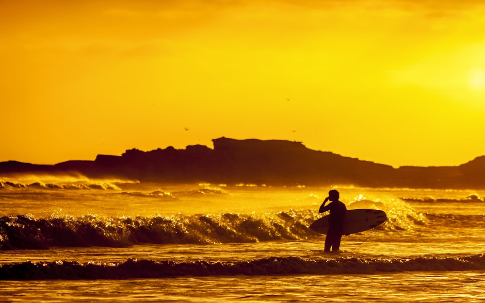 uomo che tiene la tavola da surf bianca