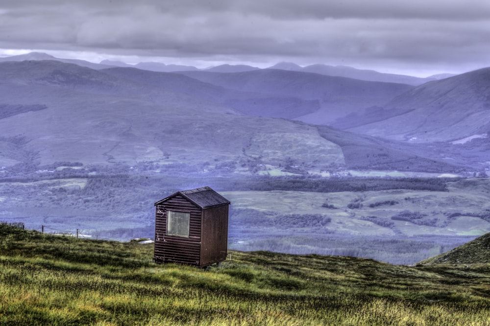 brown wooden house on green grass field near body of water during daytime