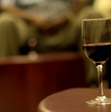 shallow focus photography of wine in wineglass on brown wooden table