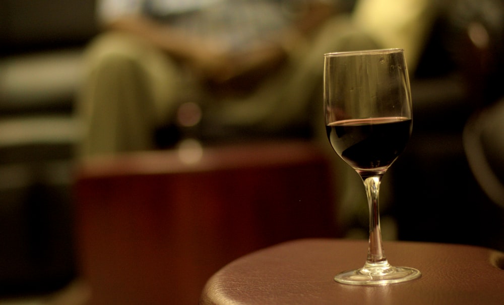 A single glass of red wine on a bar table.