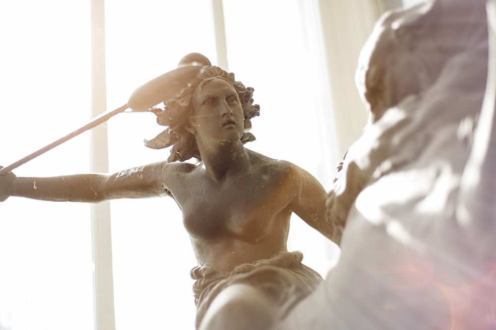 man in white shirt holding a stick statue