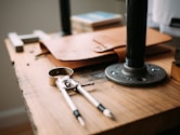 gray steel drawing compass near brown leather case