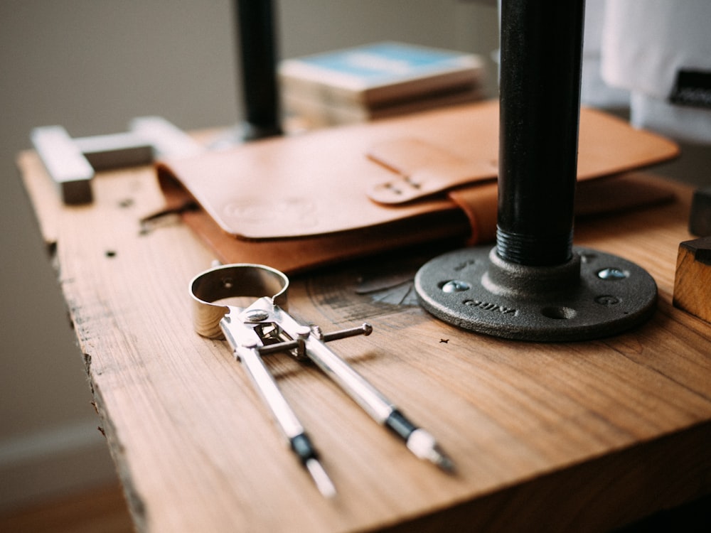 gray steel drawing compass near brown leather case