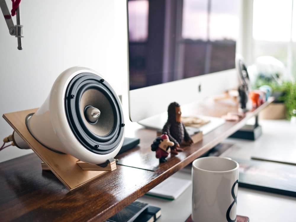 white speaker in brown holder beside silver Imac