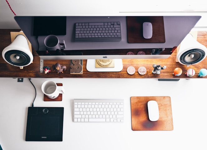 Image d'un bureau avec un ordinateur, clavier et souris Apple, décoré aux couleurs bois vu du dessus