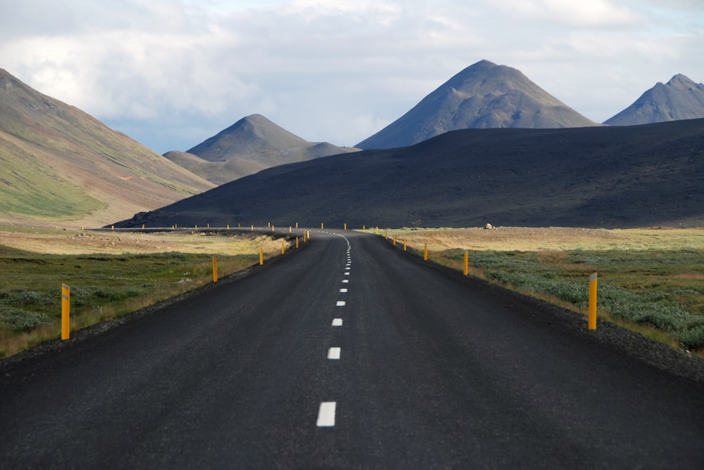 Carretera de asfalto negro entre campo de hierba