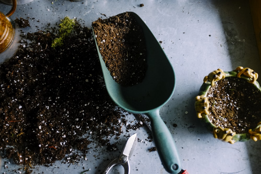 Pelle de jardin en métal vert remplie de terre brune