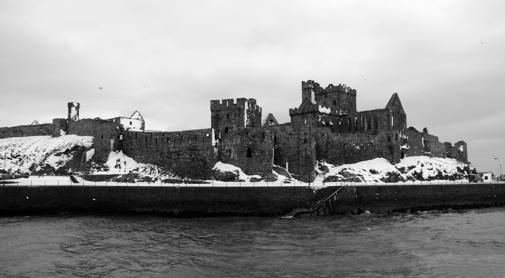 grayscale photo of concrete castle beside sea