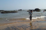 Joyful children running barefoot along a terracotta-colored coastline.