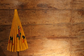 A small, foldable umbrella neatly tucked inside a matching carrying case on a wooden table.