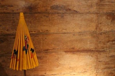 A small, foldable umbrella neatly tucked inside a matching carrying case on a wooden table.