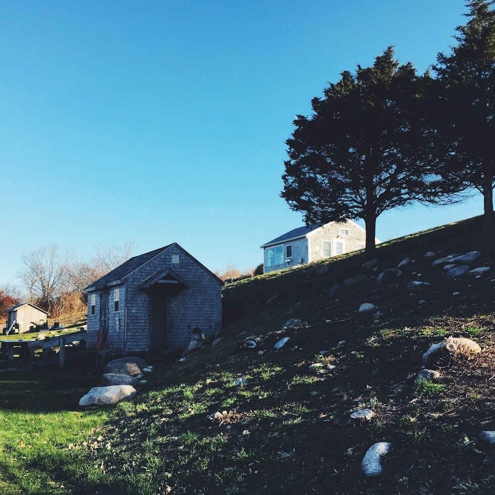 Weißes und braunes Haus in der Nähe von grünen Bäumen unter blauem Himmel während des Tages