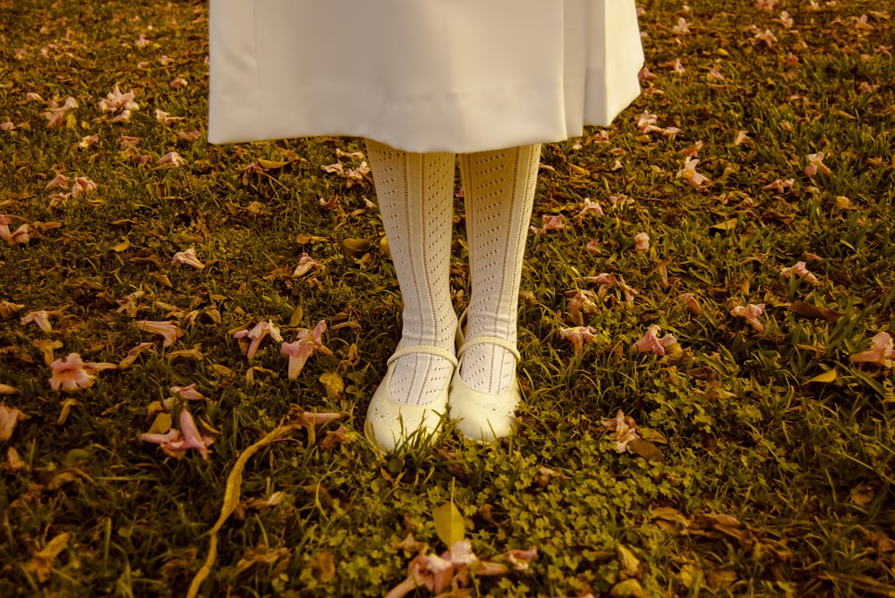 girl standing on grass wearing white dress and shoes during daytime