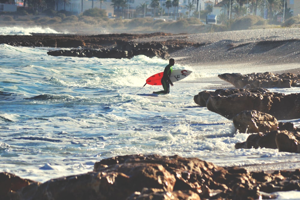 surfer walking on body of water during daytime