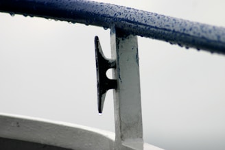 Close-up of stainless steel marine bolts and screws glistening with seawater droplets on a boat deck.
