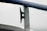 A close-up of a metal cleat on a boat railing, covered with water droplets from recent rain, against a pale, overcast sky.