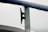 A close-up of a metal cleat on a boat railing, covered with water droplets from recent rain, against a pale, overcast sky.